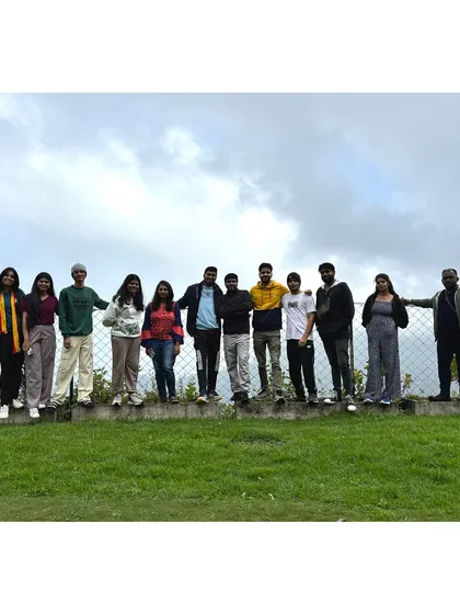 The group lined up on a wall, with the expansive green hills of Kodaikanal behind them.