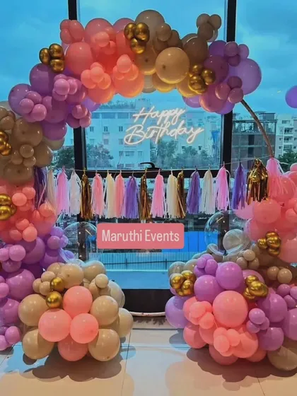 An elegant balloon arch in retro colors like dusty rose, mauve, and beige. The neon sign and tassel garland add a touch of modern style.