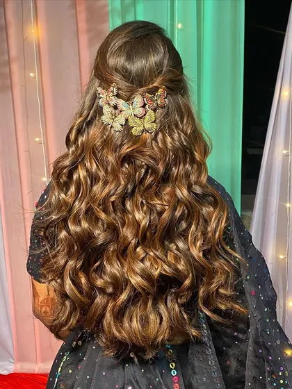A beautiful shot of the bride's hairstyle. The voluminous curls are adorned with butterfly clips, adding a playful touch to the glamorous look.