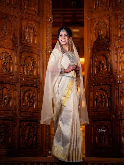 This stunning Iyer bride wanted to honor her groom's heritage by wearing a Kannadiga-style drape for one of her ceremonies. I created this elegant look for her, blending traditions beautifully against the backdrop of an intricately carved wooden doorway.
