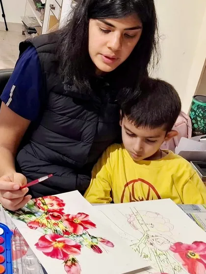 I encourage artistic development at every age. Here, an older student provides gentle guidance to a younger child as they work together on a beautiful floral watercolor painting.