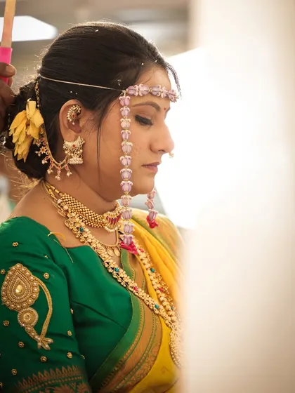 A side profile of the bride during a ritual. This highlights her elegant hairstyle and the traditional jewellery she is wearing.