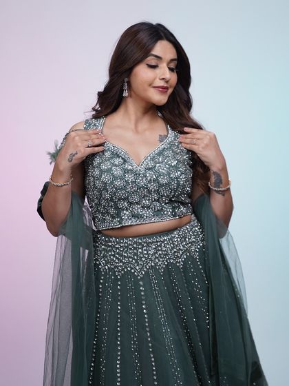 A closer look at the dark green lehenga, focusing on the detailed sequin and beadwork on the blouse and skirt.