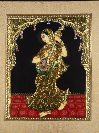 A high-quality capture of a framed Tanjore painting showing a woman playing a sitar, with perfect lighting to avoid glare and show detail.