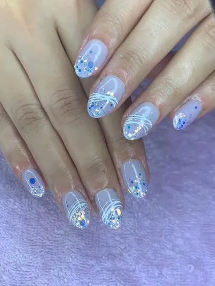 A delicate and sparkly design with a sheer blue base, encapsulated blue glitter, and fine white line art.