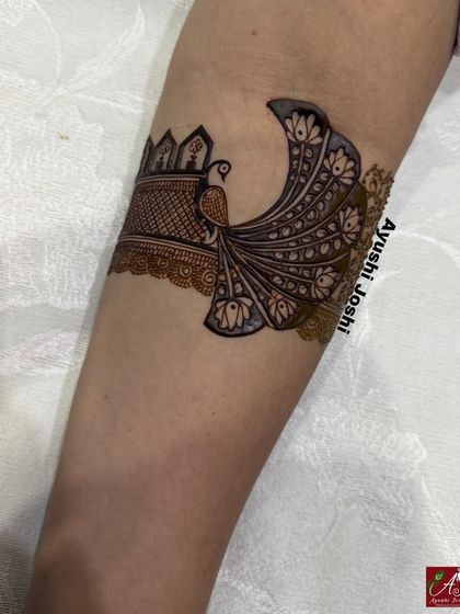 A stunning peacock with a long, flowing tail, designed as a statement piece on the upper arm.