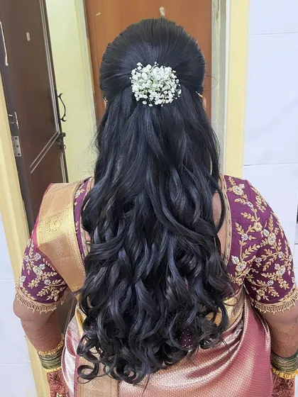 A simple and elegant half-updo with soft curls, adorned with fresh baby's breath. This is a beautiful and romantic choice for a reception or engagement.