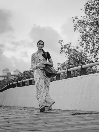 A full-length walking shot in black and white. This captures the journey and determination of a strong woman, inspired by everyday life.