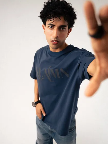 An engaging shot for a streetwear brand where the model reaches towards the camera. This dynamic pose draws the viewer in and showcases the t-shirt's design in a creative, interactive way.