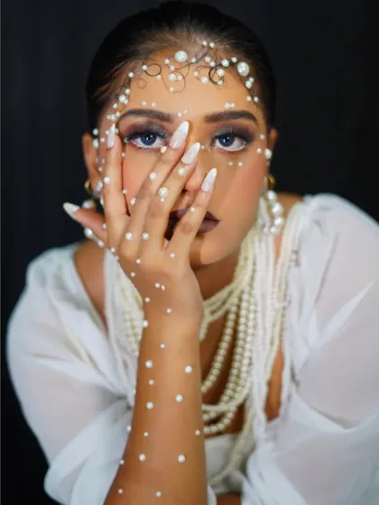 A high-fashion editorial look, with the model's face partially obscured to draw attention to the pearl details.