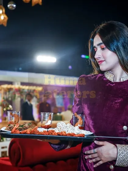 A member of our serving staff in an elegant velvet uniform, holding a tray of appetizers. We ensure our team's appearance matches the high standard of your event.