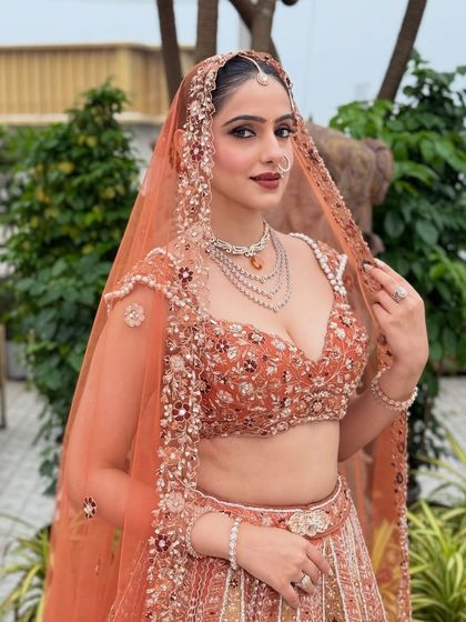 A three-quarter view of the bride, showing off her stunning lehenga and jewelry. The makeup is balanced, with bold eyes and a neutral lip to let the outfit shine.