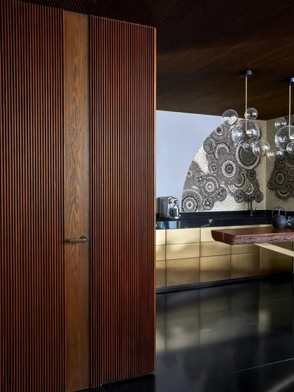 The Chai Bar area at the Baid Residence, featuring brass paneling on the storage units and a stunning Mandala art mosaic by Kesar. This space is a tribute to Indian spiritual art and craftsmanship.