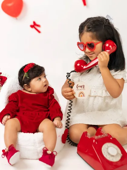 "I'm calling to say I love you!" This playful moment from a four-month Valentine's shoot shows the fun interaction between sisters.