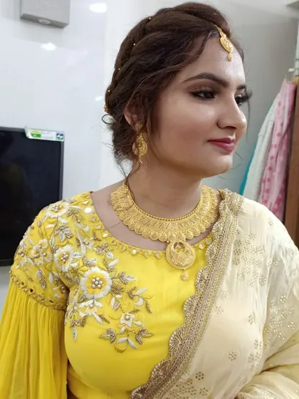 A profile view highlighting the soft, blended eyeshadow and the elegant maang tikka. Her skin looks smooth and radiant, perfect for celebrating such a special day.