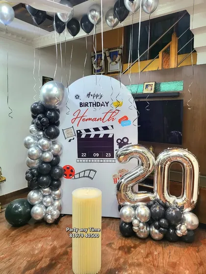 A movie-themed 20th birthday party. This custom setup includes a personalized backdrop with a film clapboard design, a balloon pillar, and helium balloons.
