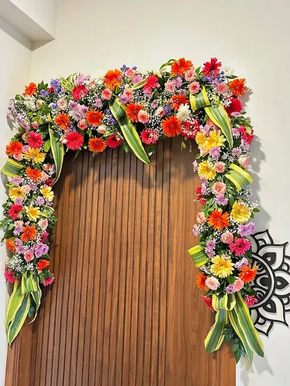 An intricate and colorful floral arch created over a doorway inside the house. We use a mix of fresh, vibrant flowers to bring life and beauty to your indoor spaces.