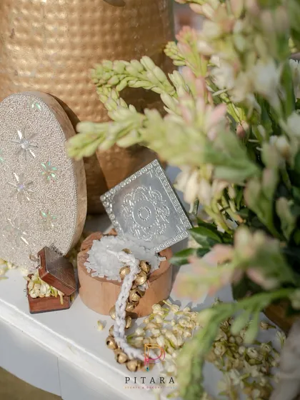 Traditional elements like ghungroos and a silver coin box are beautifully arranged with fresh jasmine, adding cultural richness to the decor.