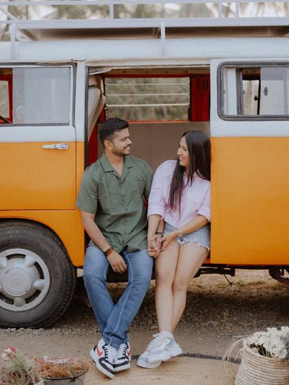 A sweet moment from a vintage van themed shoot, with the couple sitting together in the doorway holding hands.