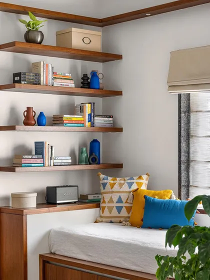 In the 'Gulmohar' family space, we designed a platform seat for lounging while watching TV. This custom piece includes storage underneath and is complemented by floating library shelves.