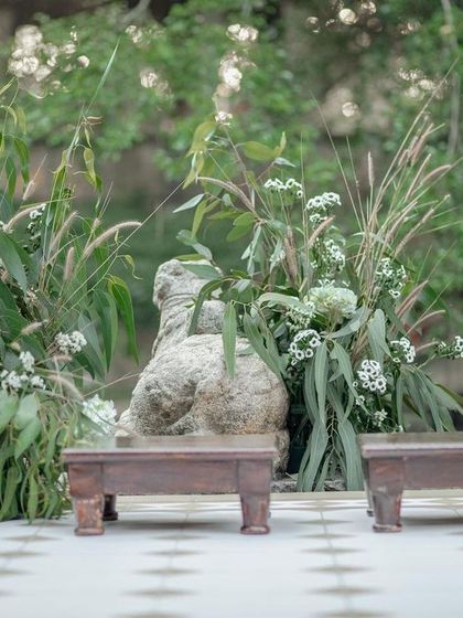 The altar for the 'Love in Ruins' wedding, featuring simple wooden stools set against a backdrop of natural grasses and white flowers.
