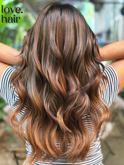 We call this one glitter and honey. This non-bleach balayage adds warm, coppery-gold dimension to a dark base, creating a beautiful glow, especially on long, wavy hair.