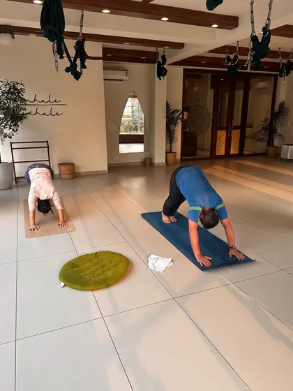 Two students practice Downward-Facing Dog, demonstrating the personal nature of the yoga journey.