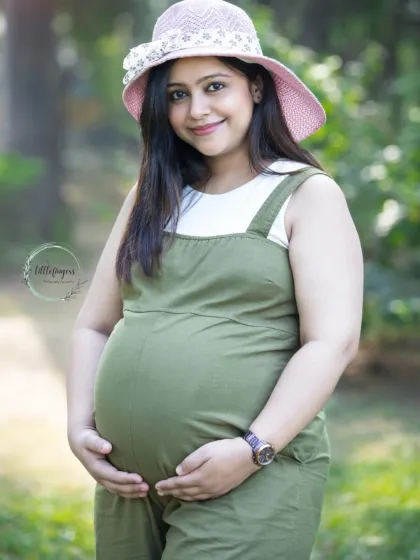 A casual and chic maternity look with an olive green jumpsuit and a sun hat. This portrait shows that you can be comfortable and stylish during your outdoor shoot.
