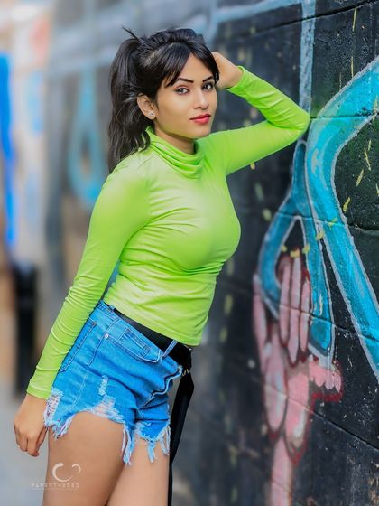 A classic fashion pose against a graffiti wall. The contrast between the bright outfit and the dark, artistic background is visually interesting.