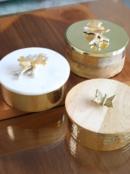 A trio of our exquisite keepsake boxes, showcasing the different designs available. From marble and wood to hammered metal, each box is a unique piece designed to hold your most precious items.