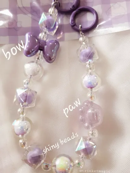 This purple bag charm features shiny, geometric beads, a glossy bow, and a paw print charm, making it perfect for dog lovers with a kawaii aesthetic.