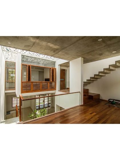 The interior of the Cube Square house is organized around a double-height volume with a floating staircase and a bridge. The design maximizes space and light in a compact plot.