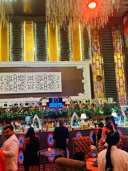 A grand bar setup with an 'I Love Shots' sign, part of a massive, opulent event space.
