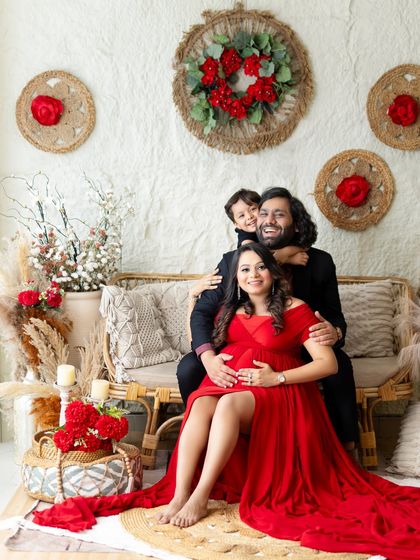 A joyful family maternity photo in my boho studio. The mom-to-be's red dress is a beautiful pop of color against the neutral, rustic background.