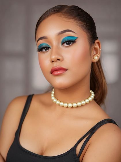 A fusion makeup look with a bold, graphic teal winged eyeshadow. Paired with a simple pearl necklace, this look is a perfect blend of modern art and classic elegance.