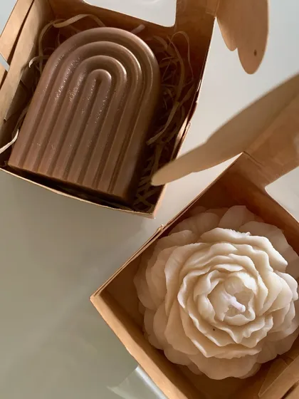 A close-up of our aesthetic soy wax candles. The set includes a modern rainbow-arch candle and a classic peony flower candle, both perfect as standalone gifts or as part of a larger hamper.
