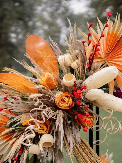 The color and texture palette for the "Colours of Autumn" theme, featuring dried palm leaves, pampas grass, corn husks, and warm-toned roses.