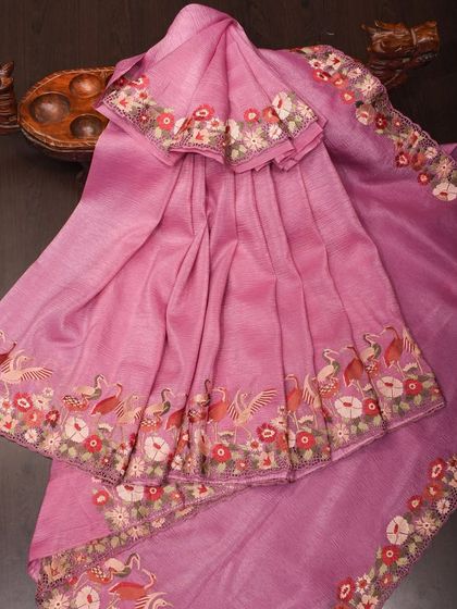 A pink linen-blend saree with a stunning embroidered border featuring peacocks and flowers. This piece combines the comfort of linen with the glamour of party wear.