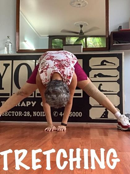 A wide-legged forward bend, incorporating sneakers to show that yoga can be adapted. The focus is on the stretch, not the attire.