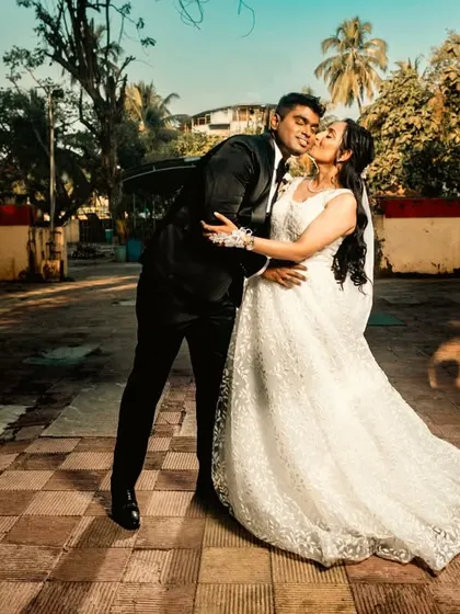 A beautiful, wide-angle shot capturing a romantic kiss in the golden hour light. The composition gives a sense of place while keeping the focus on their intimate moment.