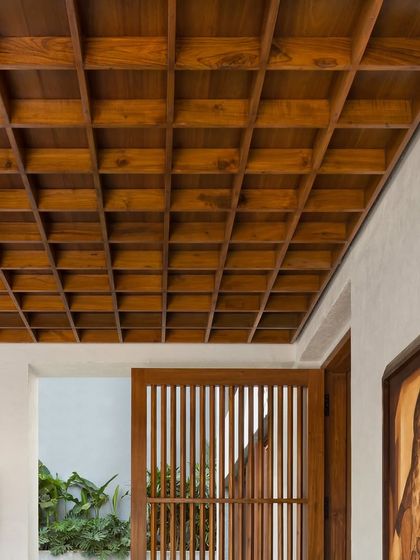 The entrance to the House of Terraces features a striking coffered wooden ceiling. This detail immediately establishes a sense of warmth, craftsmanship, and architectural integrity.