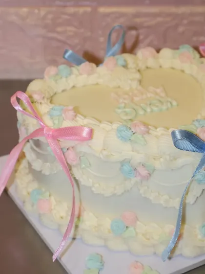 The delicate details on this baby shower cake, from the pastel rosettes to the flowing ribbons, make it a truly special centerpiece.