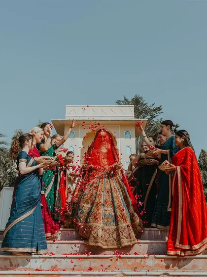 The bride's grand entrance at a beautiful Rajasthan wedding, showered with petals by her bridesmaids. This is a moment of pure celebration and anticipation, captured in its full glory.