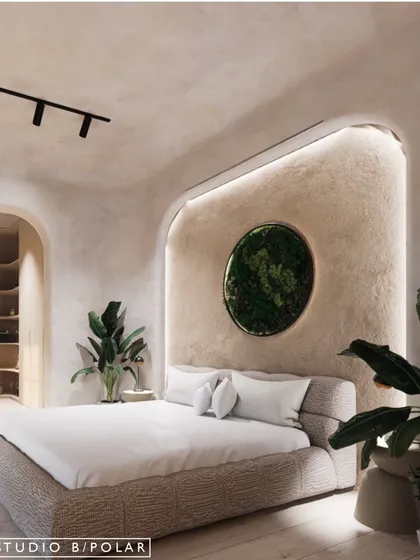 The bed is set against a softly arched niche with integrated backlighting. A circular moss art installation adds a touch of biophilic design, bringing a living, natural element into the room.