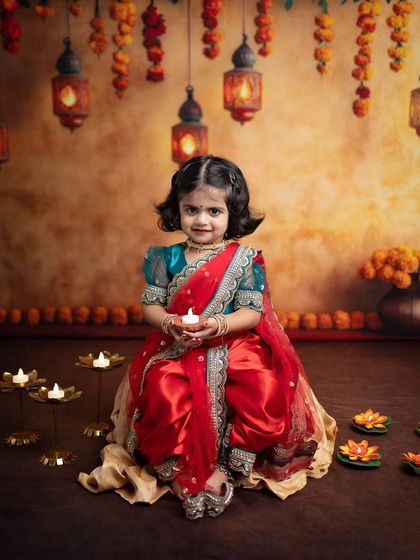 Holding a diya, she looks right at the camera with a gentle smile. This is a classic Diwali portrait that families will treasure.