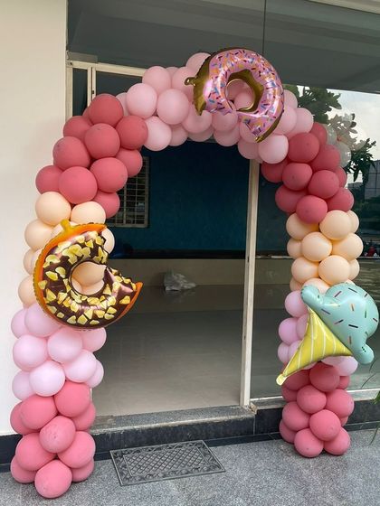 A sweet balloon arch for a candy themed party entrance, decorated with donut and ice cream foil balloons.