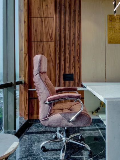 The executive chair and desk area in Mr. Siraj's cabin. The design ensures an impressive backdrop for video calls, with textured wood paneling and a view of the city skyline.