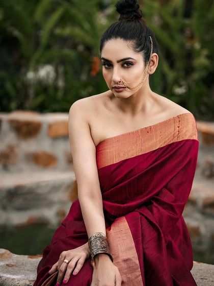 A fusion-style ethnic shoot, combining a traditional saree drape with a modern, minimalist aesthetic. The natural, stony background adds a raw and earthy feel to this confident portrait.