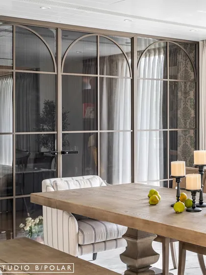 The combination of the rustic wooden table, striped upholstered armchair, and the modern classic partition creates a layered and eclectic look that is central to the home's "Dream Home Makeover" inspiration.