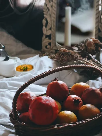 A vintage-inspired still life featuring a basket of pomegranates and oranges, creating a classic, artistic feel.